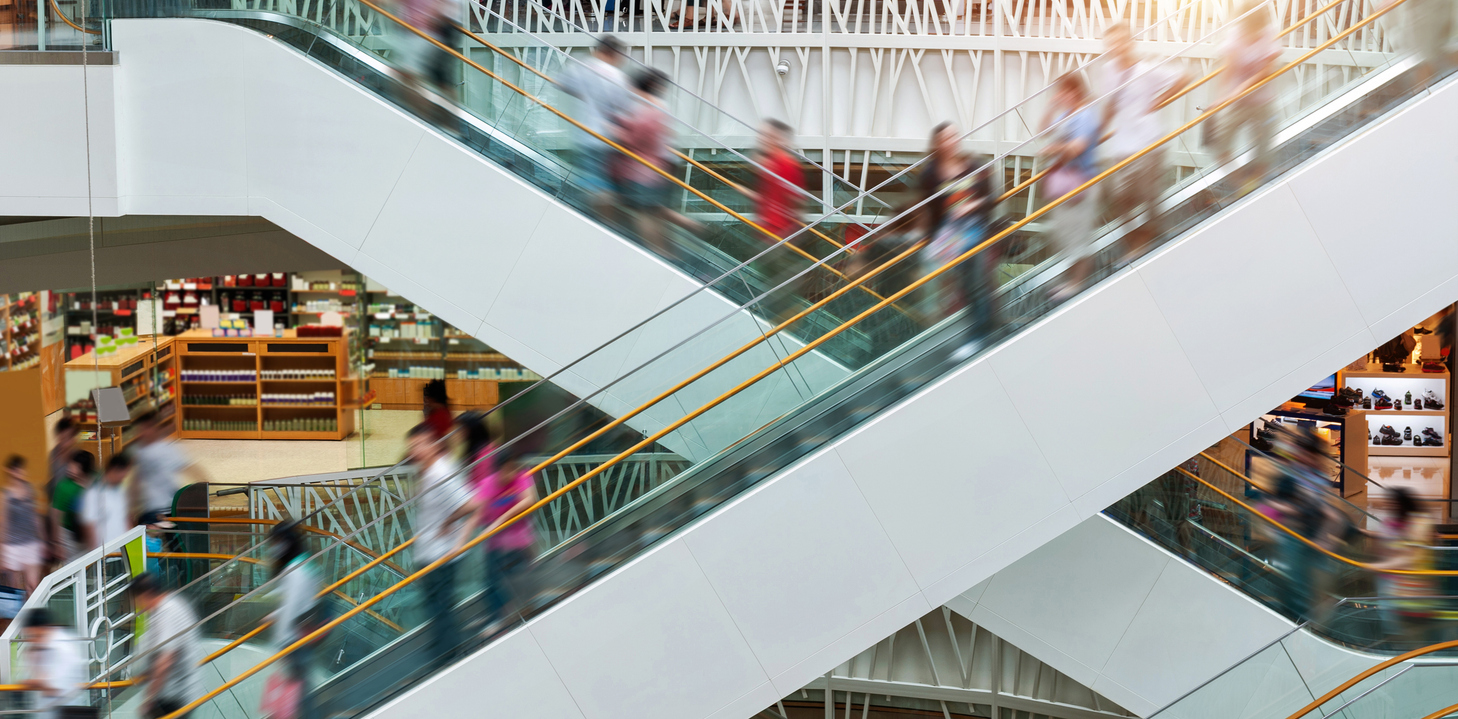 People on escalators in modern shopping mall.