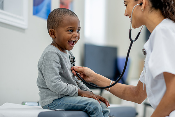 happy little boy getting his heart beat checked by a nurse