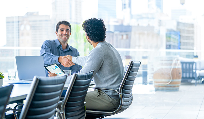 two men shaking hands in a conference room