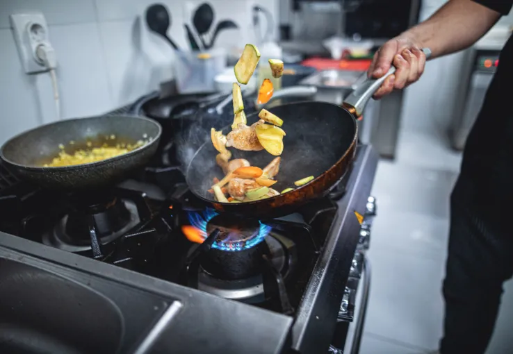 Chef flipping food as they cook in a commercial kitchen