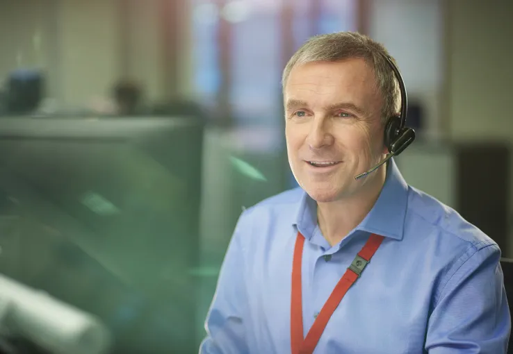 Older male in a headset who is a utility call center agent using a case management system to better serve customers.