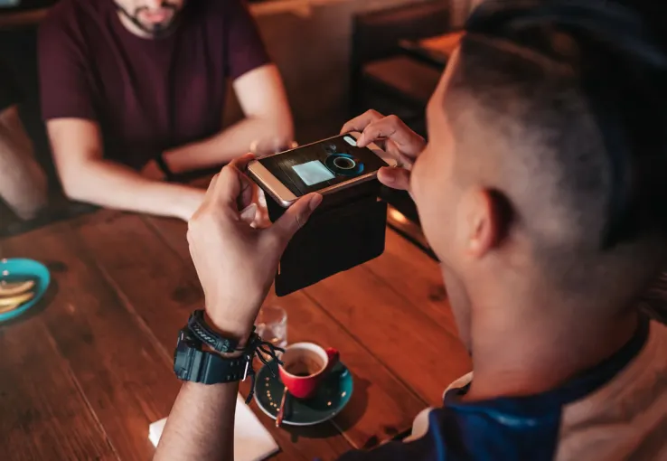 young man taking a picture of his coffee for social media